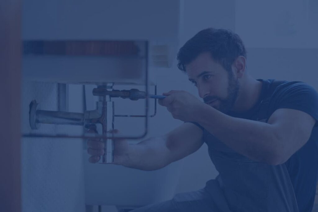 Focused plumber repairing a sink pipe, showcasing professional plumbing services and expertise in home maintenance.