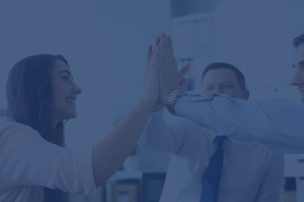 Enthusiastic team celebrating success with a group high-five in a professional office setting, symbolising teamwork, collaboration, and achievement.